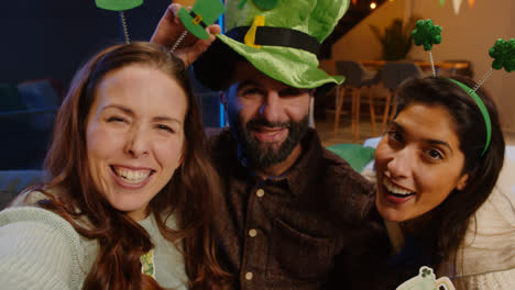 POV-Shot-Of-Friends-Dressing-Up-With-Irish-Novelties-And-Props-At-Home-Or-In-Bar-Posing-For-Selfie-Celebrating-At-St-Patrick's-Day-Party-In-Real-Time-2